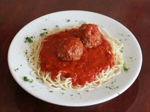 Spaghetti with green vegetables and two meatballs